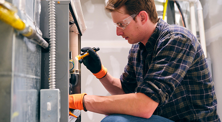 HVAC technician repairing an air conditioning unit outdoors.