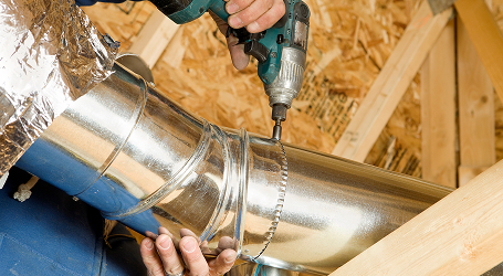 Plumber repairing a faucet beneath a bathroom sink.